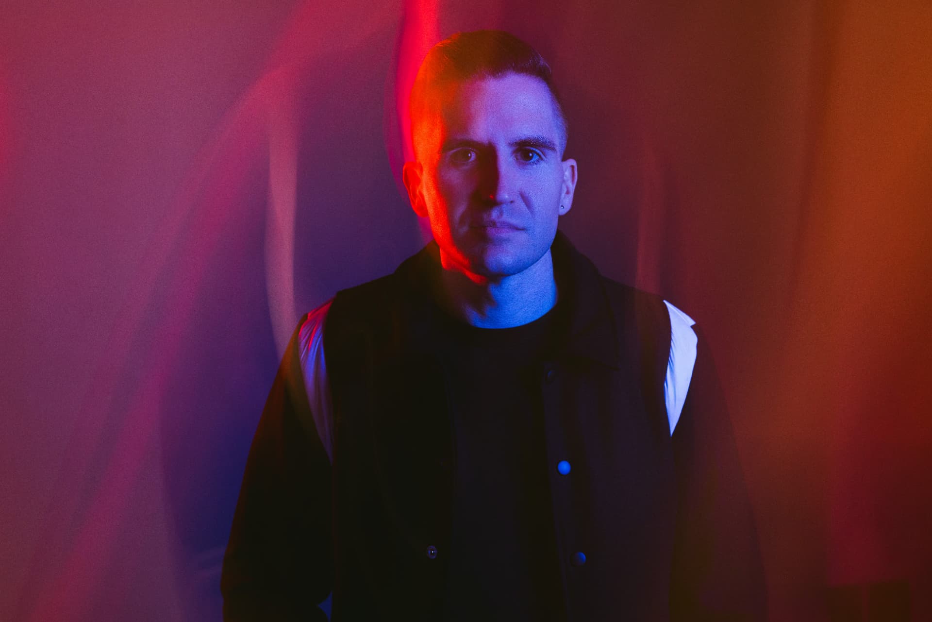 Lyndrum lit by red and blue light against a draped backdrop