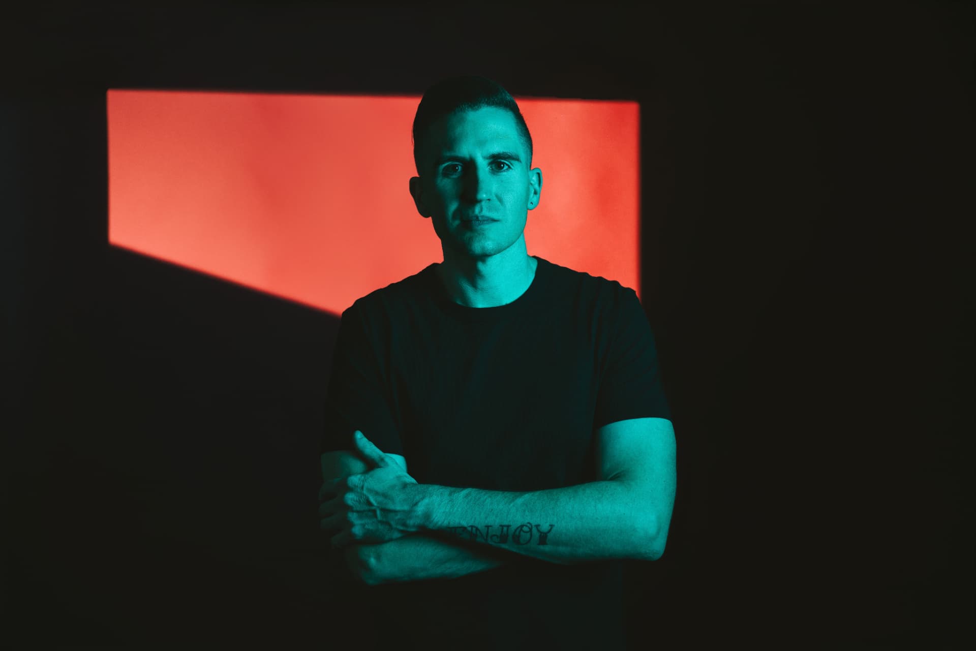 Lyndrum with arms crossed in front of a red light panel