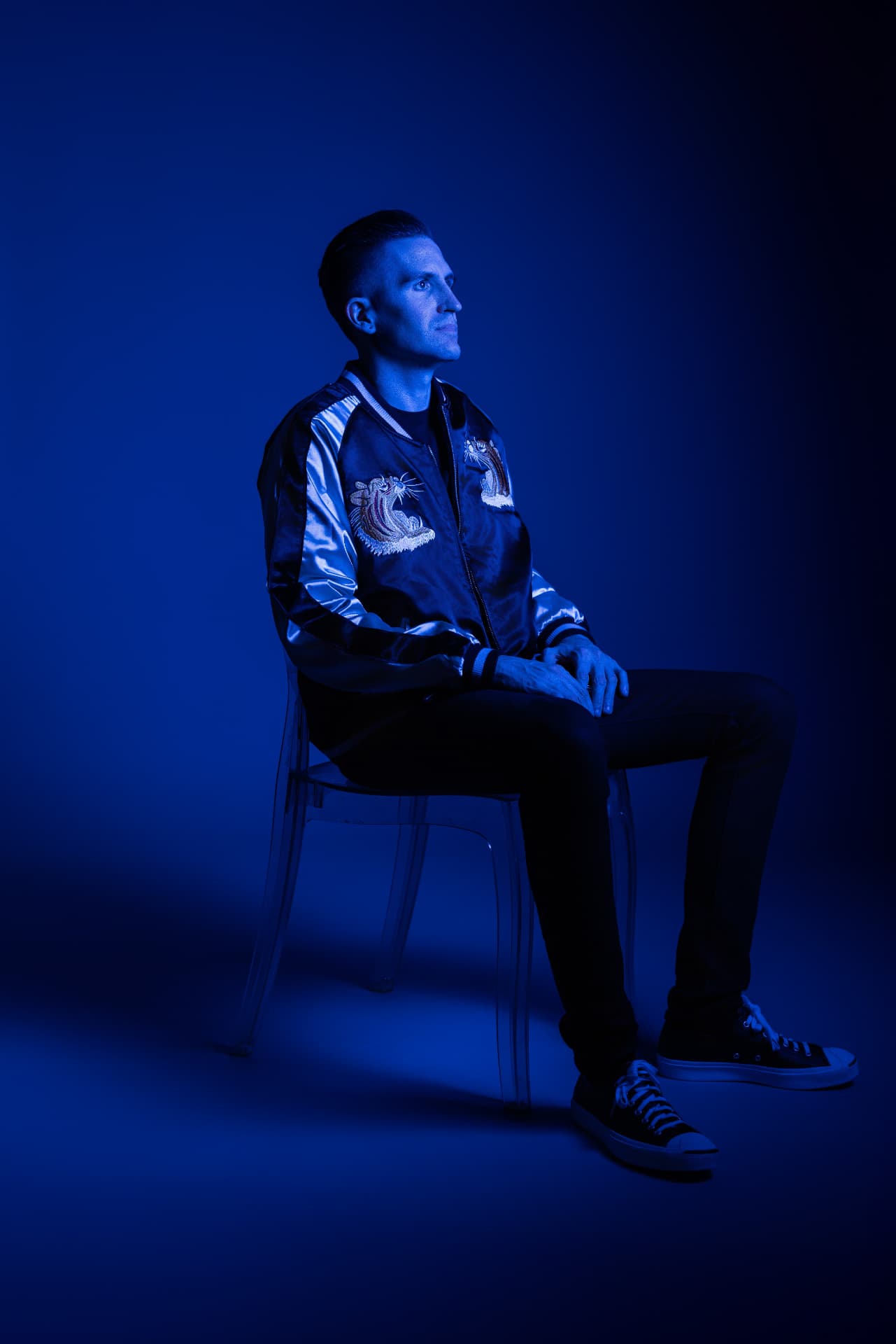 Lyndrum seated under deep blue light, photographed by Matthew Reeves